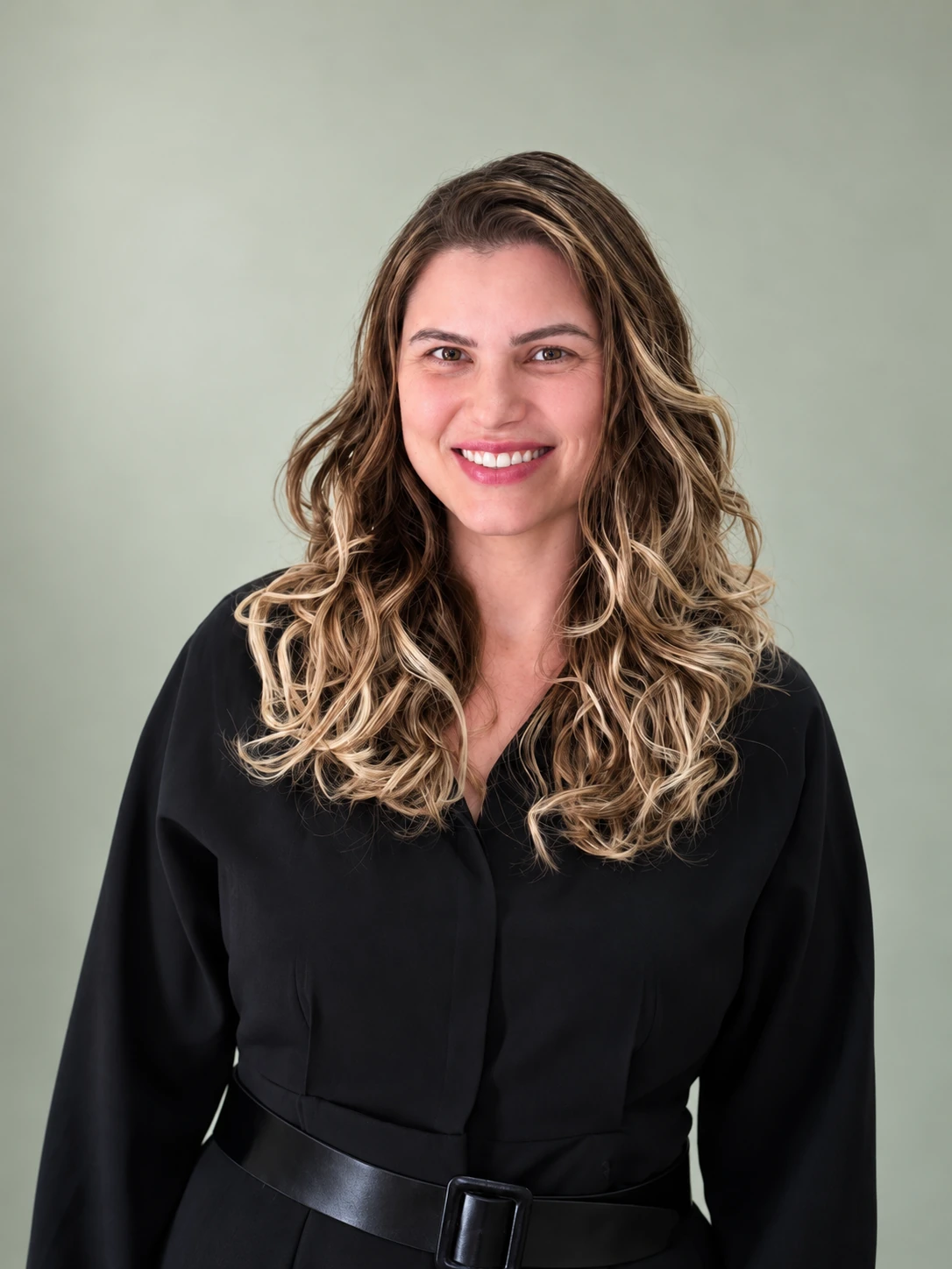 Retrato de Alice Demarco, intérprete de Libras e fundadora da Accessum, sorrindo com uma blusa preta diante de um fundo verde suave.
